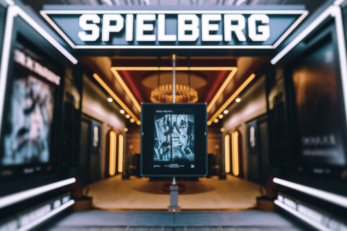 Spielberg en pleine réflexion devant écrans de montage, symbolisant l'introspection cinématographique futuriste humaniste.
